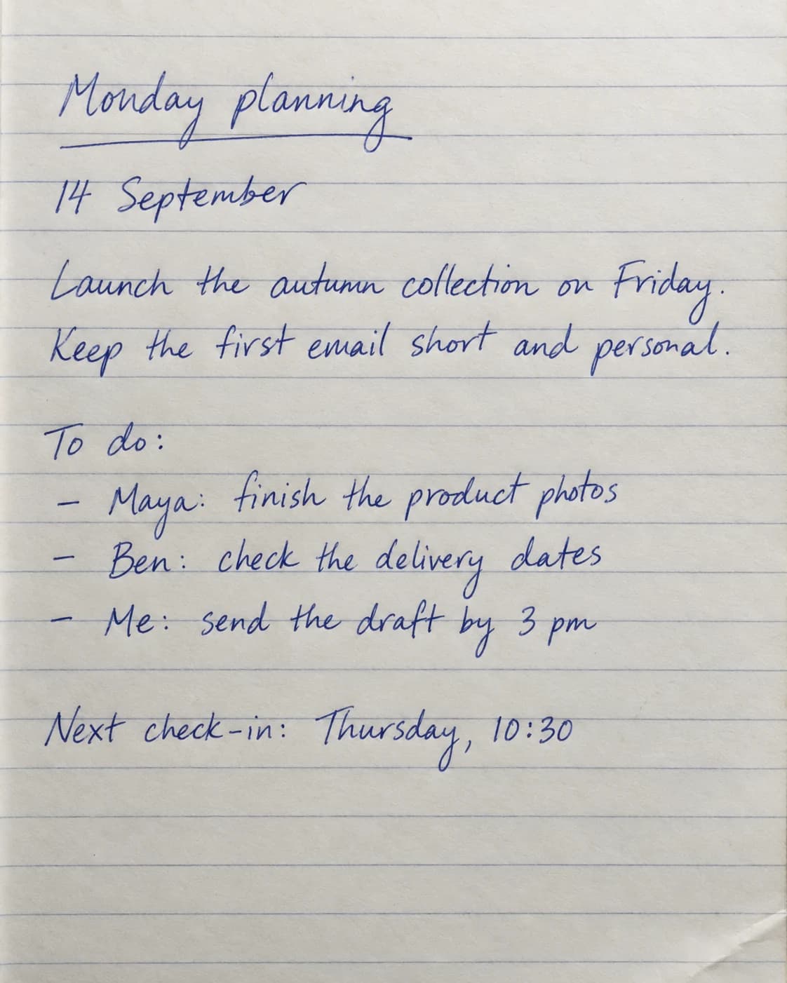Blue ballpoint planning notes on lined paper, with a date, tasks, and a meeting time.